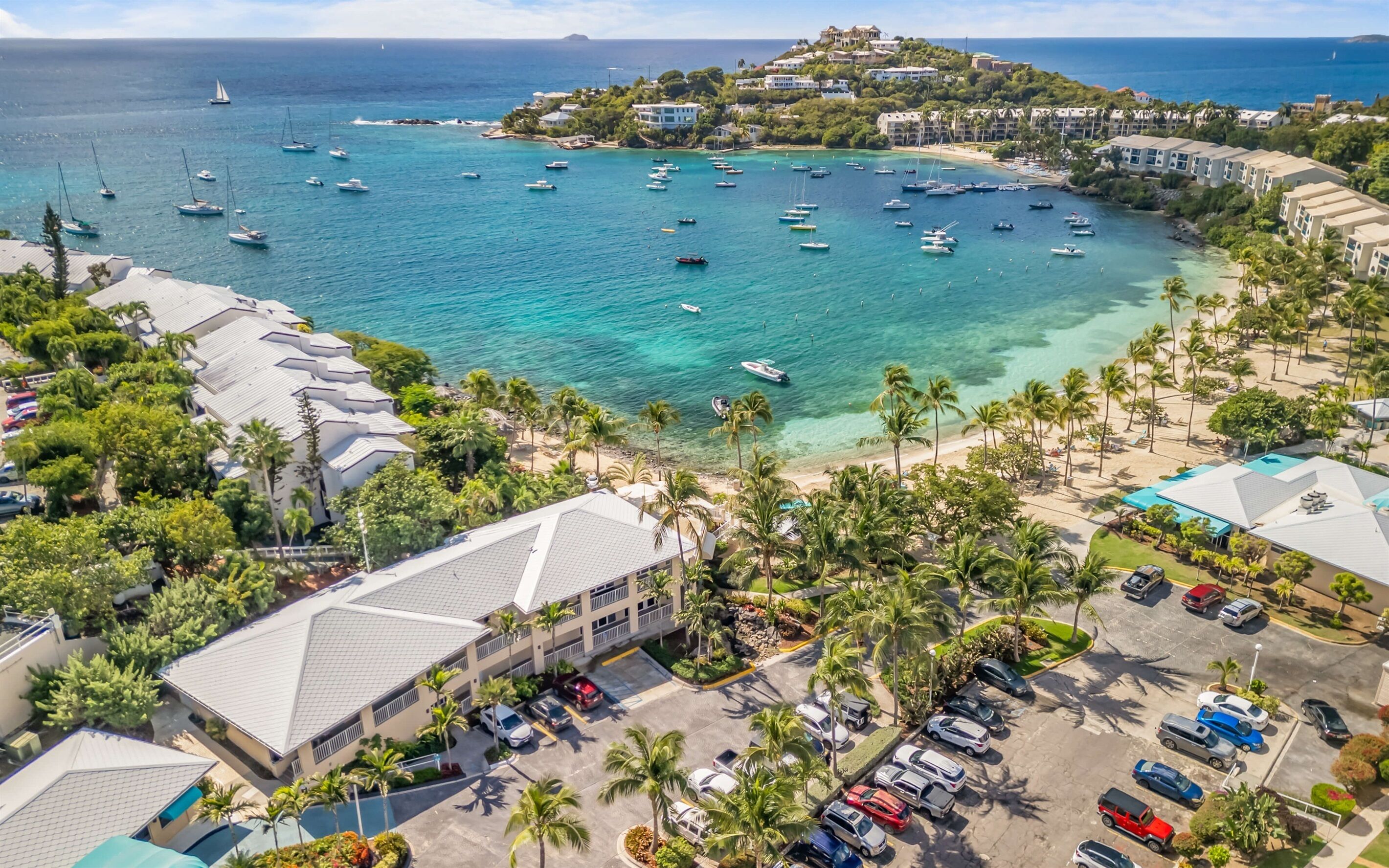 A coastal resort with multiple buildings, a marina with boats, and a parking area.