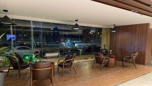 A modern interior with wooden flooring, leather chairs, and a large window overlooking a street at night. - ELITE PARK HOTEL (Jeddah)