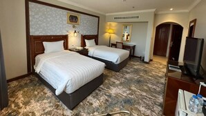 A hotel room with two beds, a desk, a chair, a TV, and a bathroom. - ELITE PARK HOTEL (Jeddah)