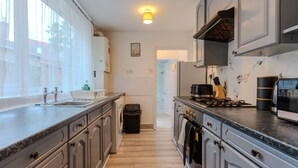 Une cuisine moderne dotée de plans de travail en granit, d’appareils électroménagers en acier inoxydable et offrant une vue sur l’extérieur.