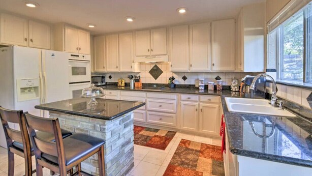 A modern kitchen with white cabinets, granite countertops, and a central island with a glass top. - 3 Bedroom with a Pool (Bedford)