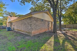 A single-story brick building with a flat roof, a small attached garage, and a fenced backyard. - 3 Bedroom with a Pool (Bedford)