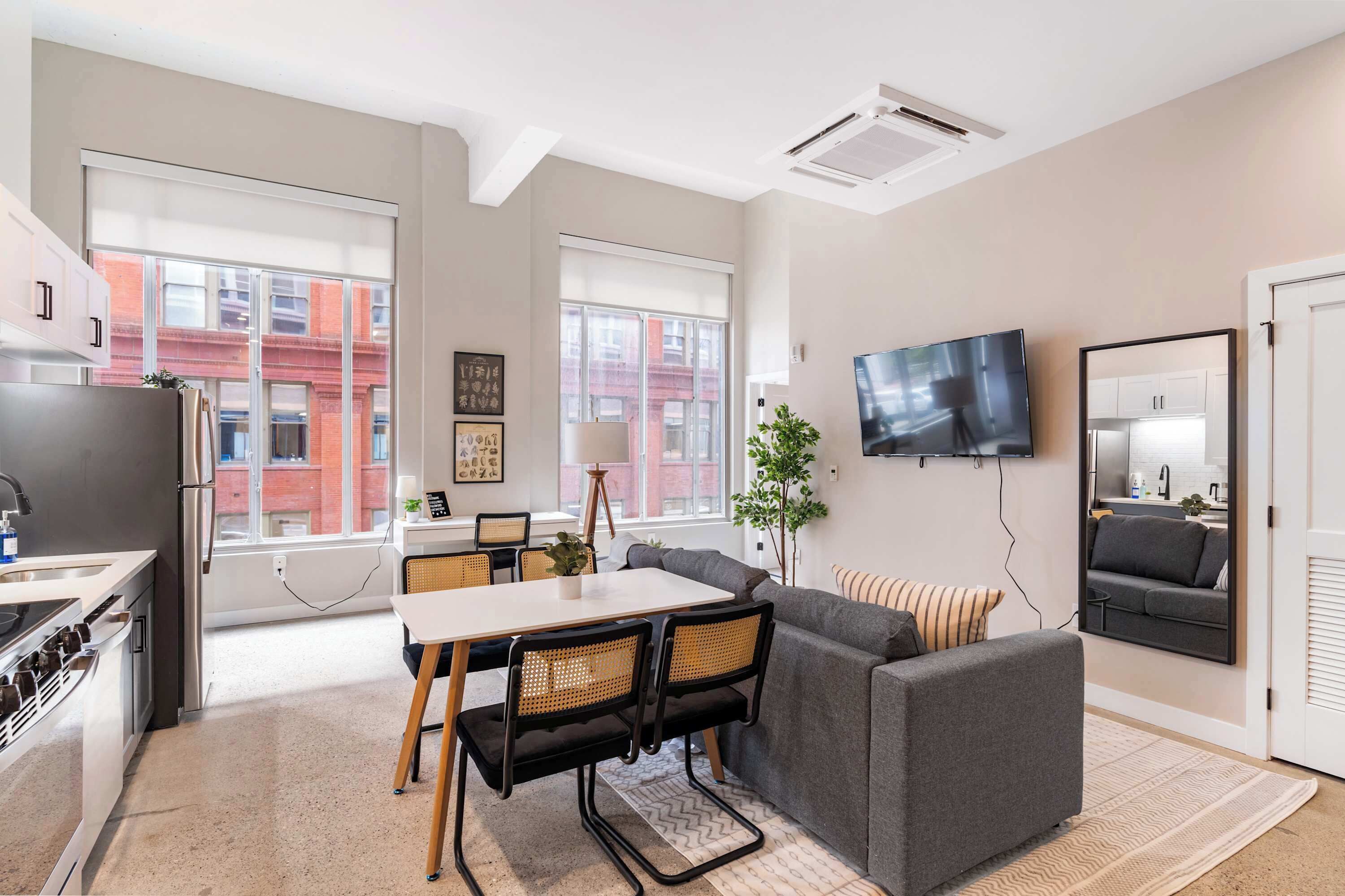 Un apartamento moderno con cocina, comedor y sala de estar. Cuenta con ventanas amplias, un televisor de pantalla plana y un sofá.