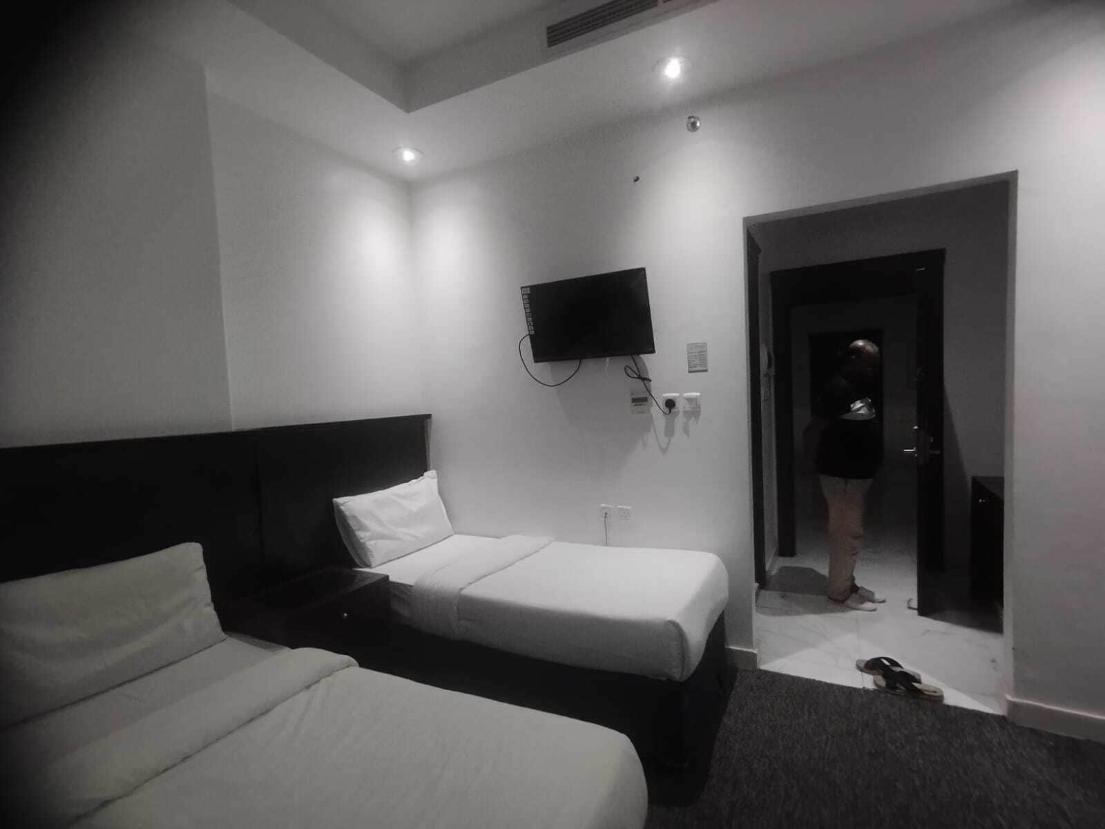 Camera d'albergo con due letti, una TV a schermo piatto montata a parete e un'uscita che dà su un corridoio.