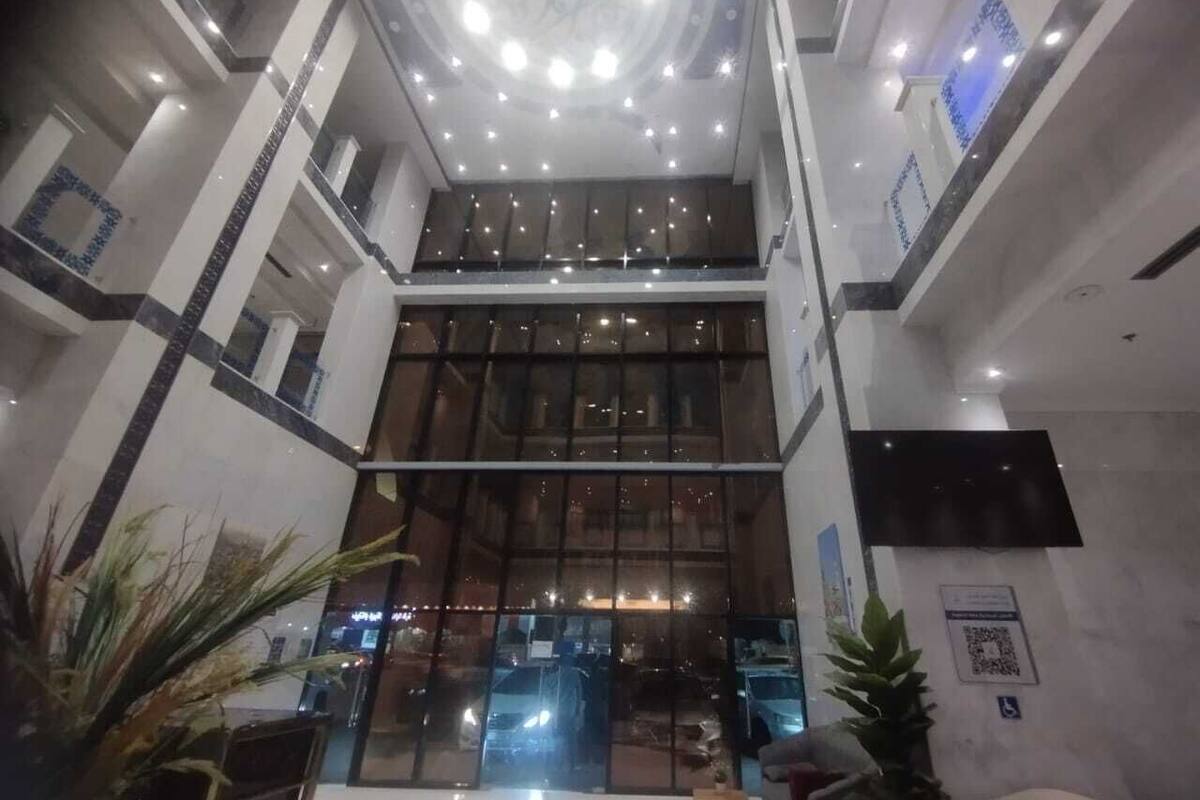 A multi-level atrium with a glass facade, a central chandelier, and a modern design.
