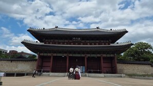 Un edificio tradicional coreano con un amplio patio central, tejado de tejas y pared de piedra.