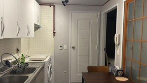 Una cocina compacta con lavamanos, lavadora y comedor con mesa y sillas.