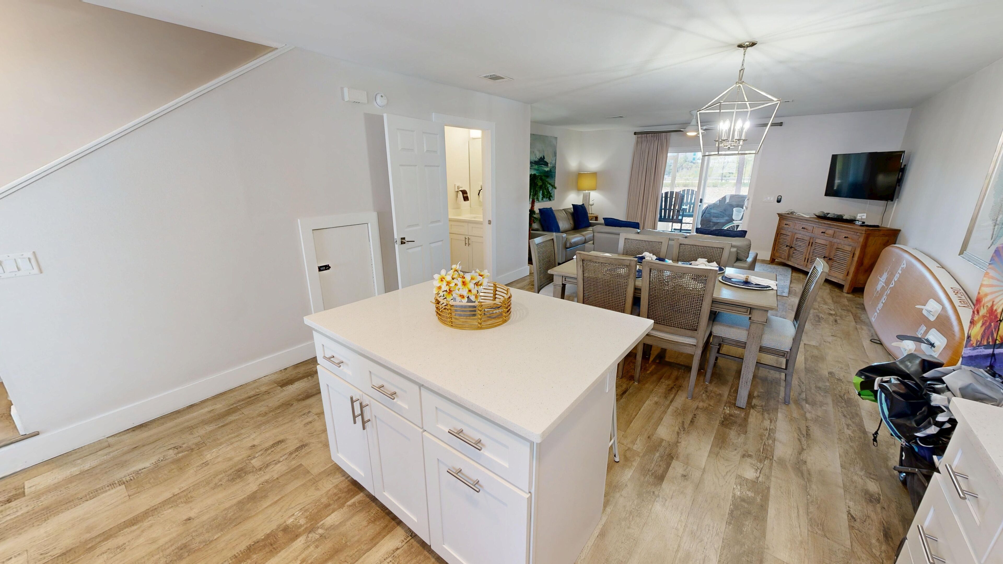 A modern kitchen with white cabinetry, a central island with a decorative bowl, and a dining area with a table and chairs.