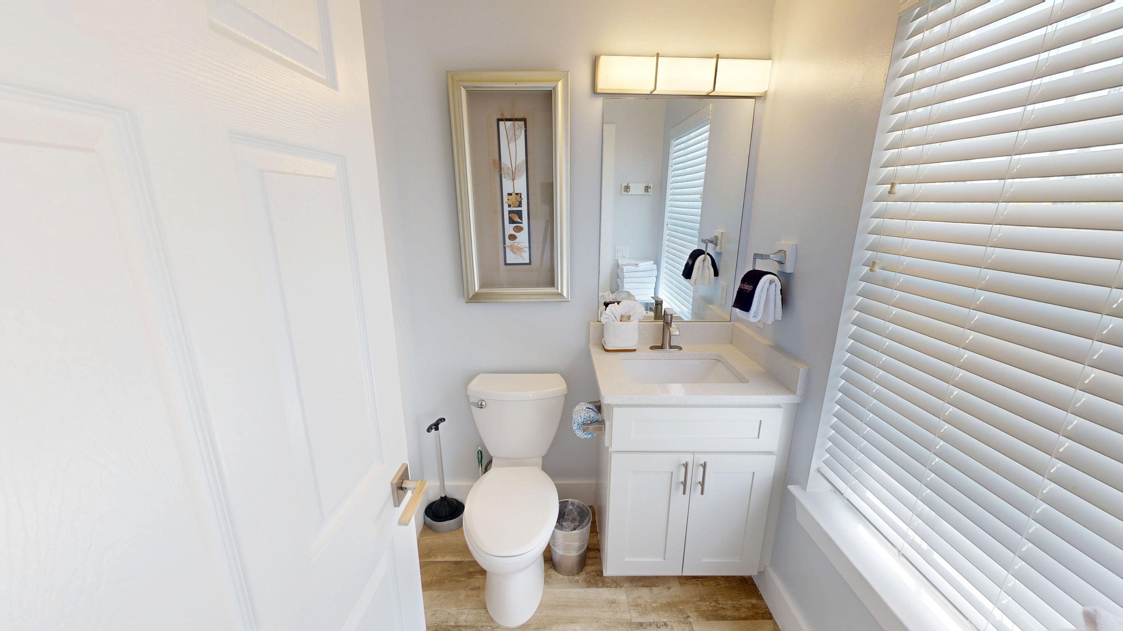 A compact bathroom with a toilet, sink, and mirror.