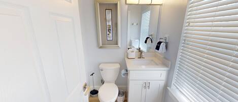 A compact bathroom with a toilet, sink, and mirror.