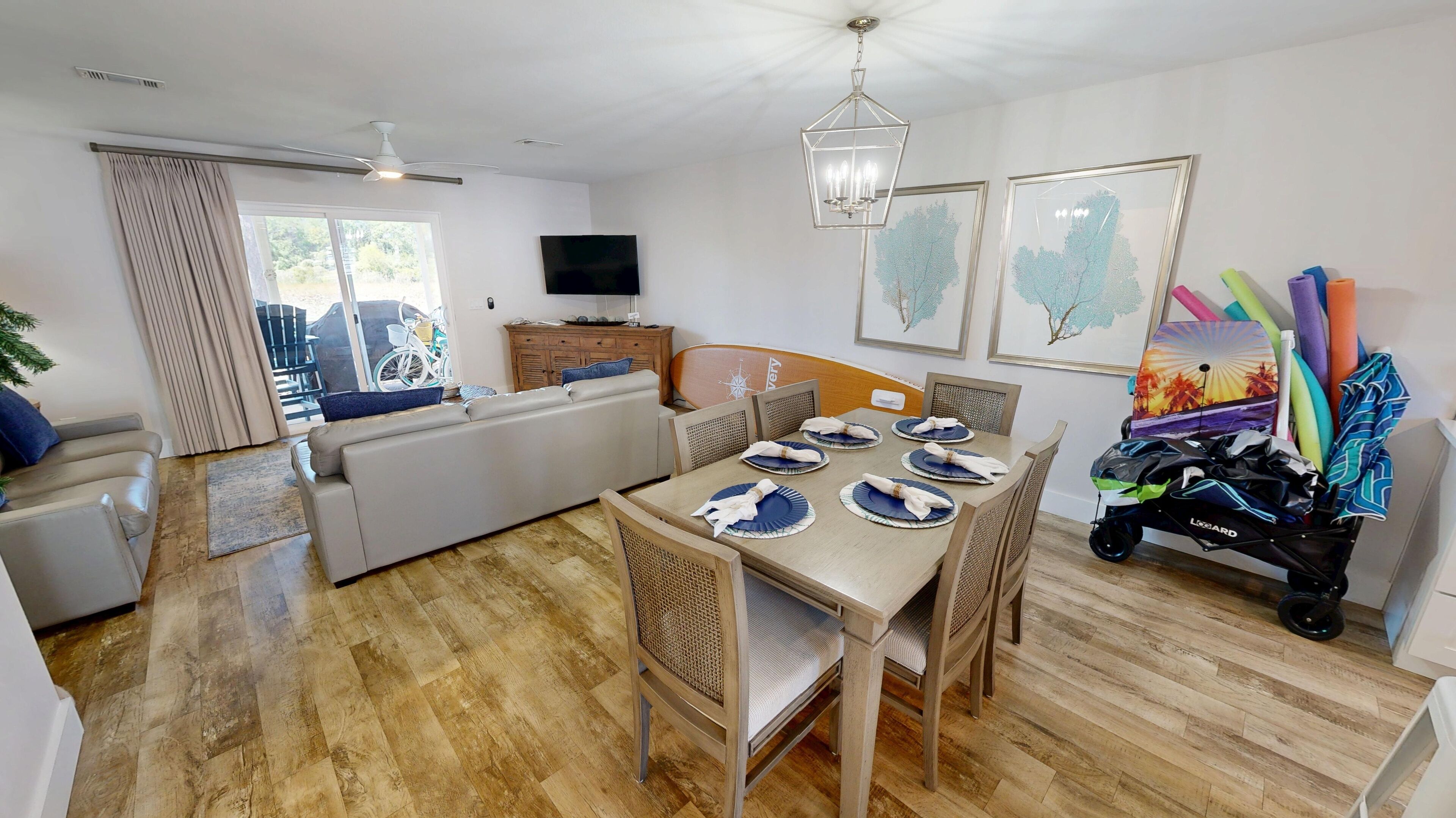 A modern living room with a dining area, wooden flooring, and a television on the wall.