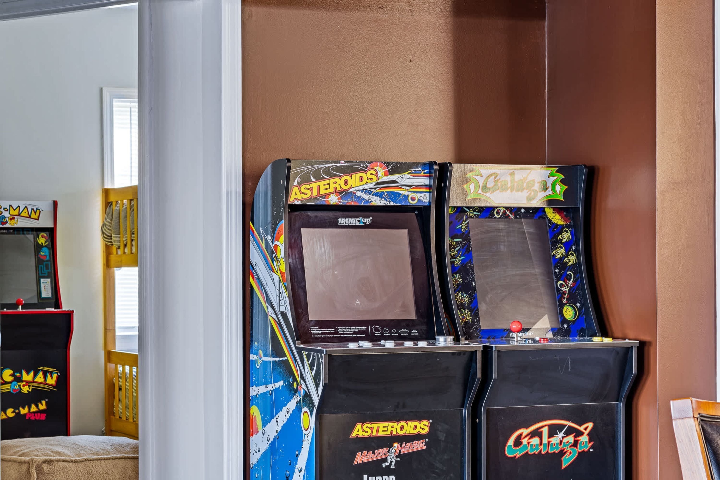 Une salle avec des jeux d’arcade, notamment Asteroids et Galaga, ainsi qu’une machine Pac-Man.
