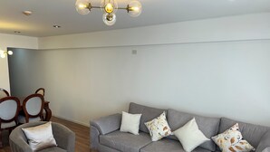 A modern living room with a grey sofa, matching armchairs, and a small white coffee table. - Elegant and Centrally Located Vallecito Apartment (Arequipa)