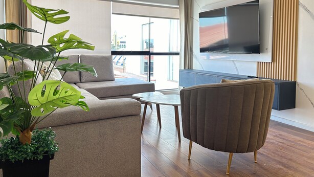 A modern living room with a sofa, a chair, a coffee table, and a large TV mounted on the wall. - Elegant and Centrally Located Vallecito Apartment (Arequipa)