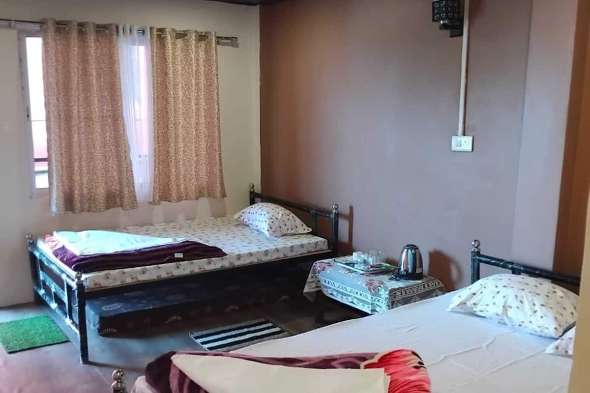 A room with two beds, a small table, and a window with curtains.
