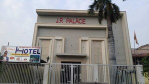 A building labeled 'J.R. Palace' with a sign for 'TP Palace Hotel' advertising luxury rooms, a restaurant, and banquet hall.
