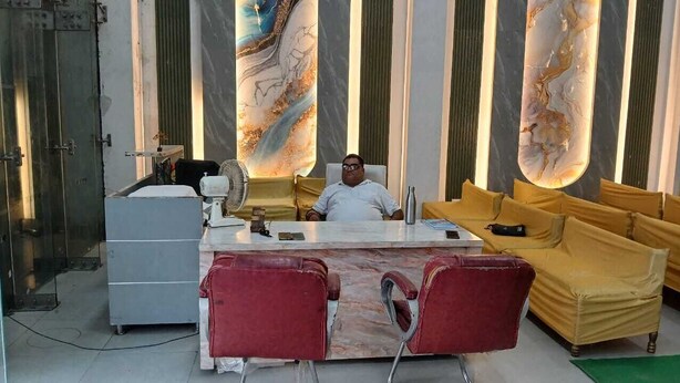 A reception area with a marble counter, red chairs, a yellow sofa, and a large abstract painting on the wall.