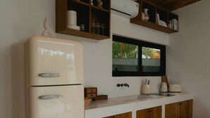 Una cocina con un refrigerador blanco, gabinetes de madera, un ventanal y una encimera con electrodomésticos.
