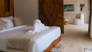 Habitación de hotel con una cama grande, un muro decorativo de madera, un cuadro y un área de descanso con una silla y una mesita.