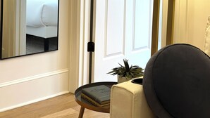 A room with a large mirror, a bed with blue pillows, a lamp, and a small table with a plant and books. - Downtown 1BR Retreat – Walk to PPAC – Kitchen & W/D (Providence)