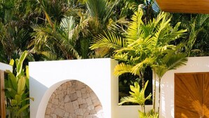 A poolside lounge area with a stone wall, a wooden door, and lush tropical plants. - 1 Bedroom Island Retreat central located (Bo Phut)