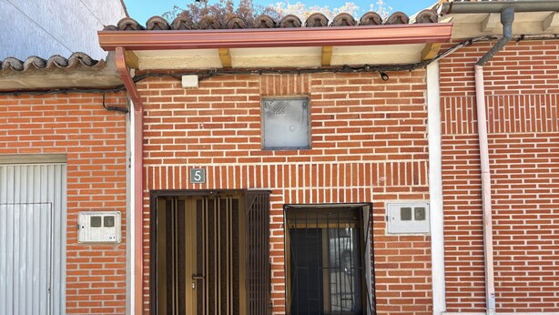 Un bâtiment en briques avec une porte numérotée, une fenêtre et un portail en métal.