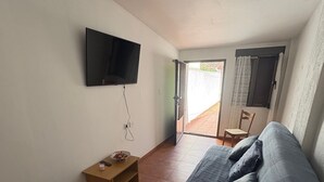 Une chambre à coucher avec un lit, un téléviseur fixé au mur, une petite table en bois et une chaise.