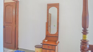 A wooden dresser with a mirror, a closed wooden door, and a trash can. - Blue Water Paradise Akurala (Akurala)