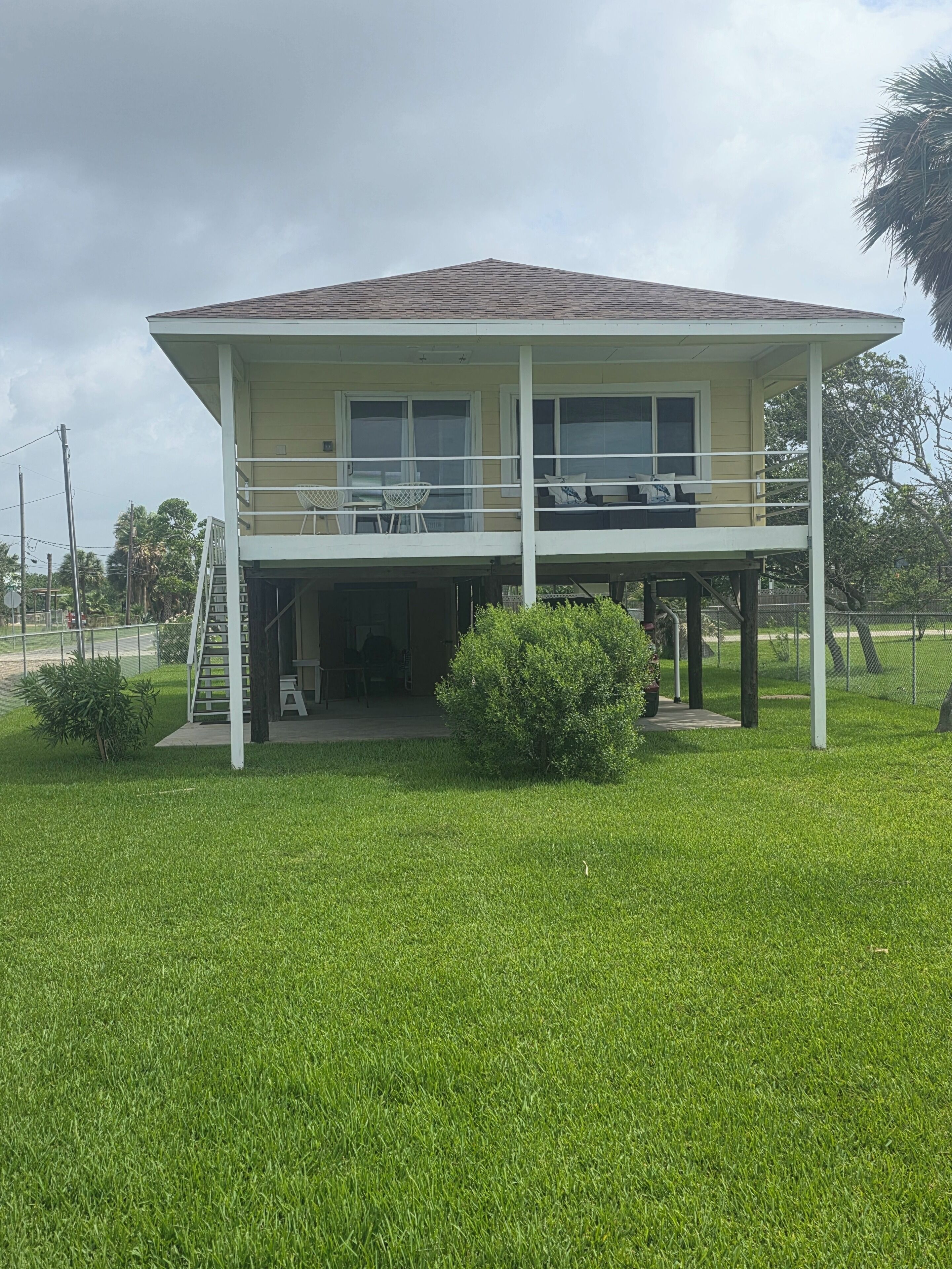 A two-story house with a balcony, a covered porch, and a small garden area.