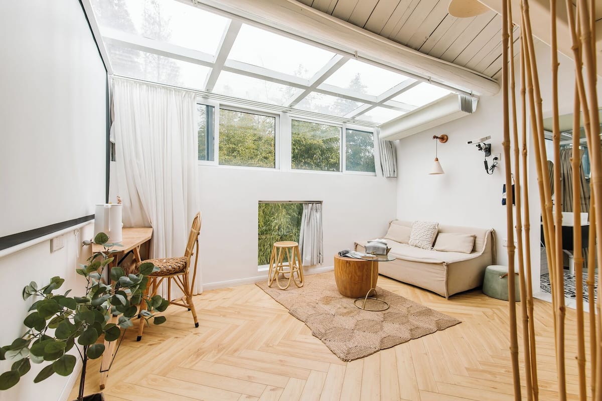Una habitación amplia con un gran tragaluz, un sofá, un comedor con mesa y sillas, y suelo de madera.