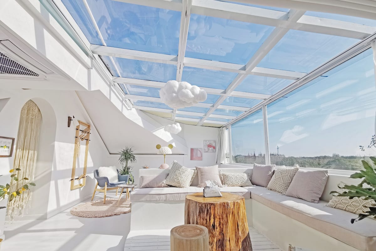 Amplia sala de estar con diseño abierto, techo alto y tragaluces, que incluye un conjunto de sofás, una mesa de centro de madera y vistas al exterior.