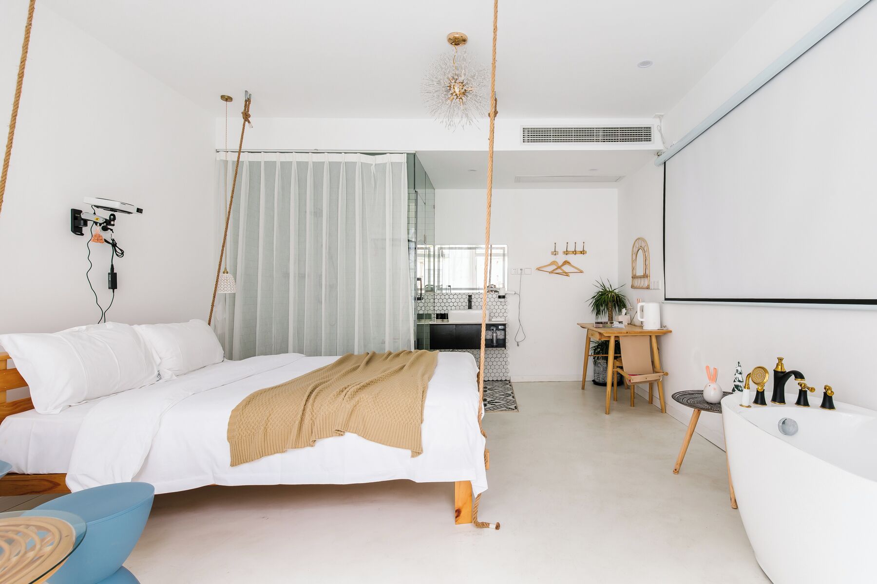 A modern bedroom with a bed, bedside table, and a desk with a chair.