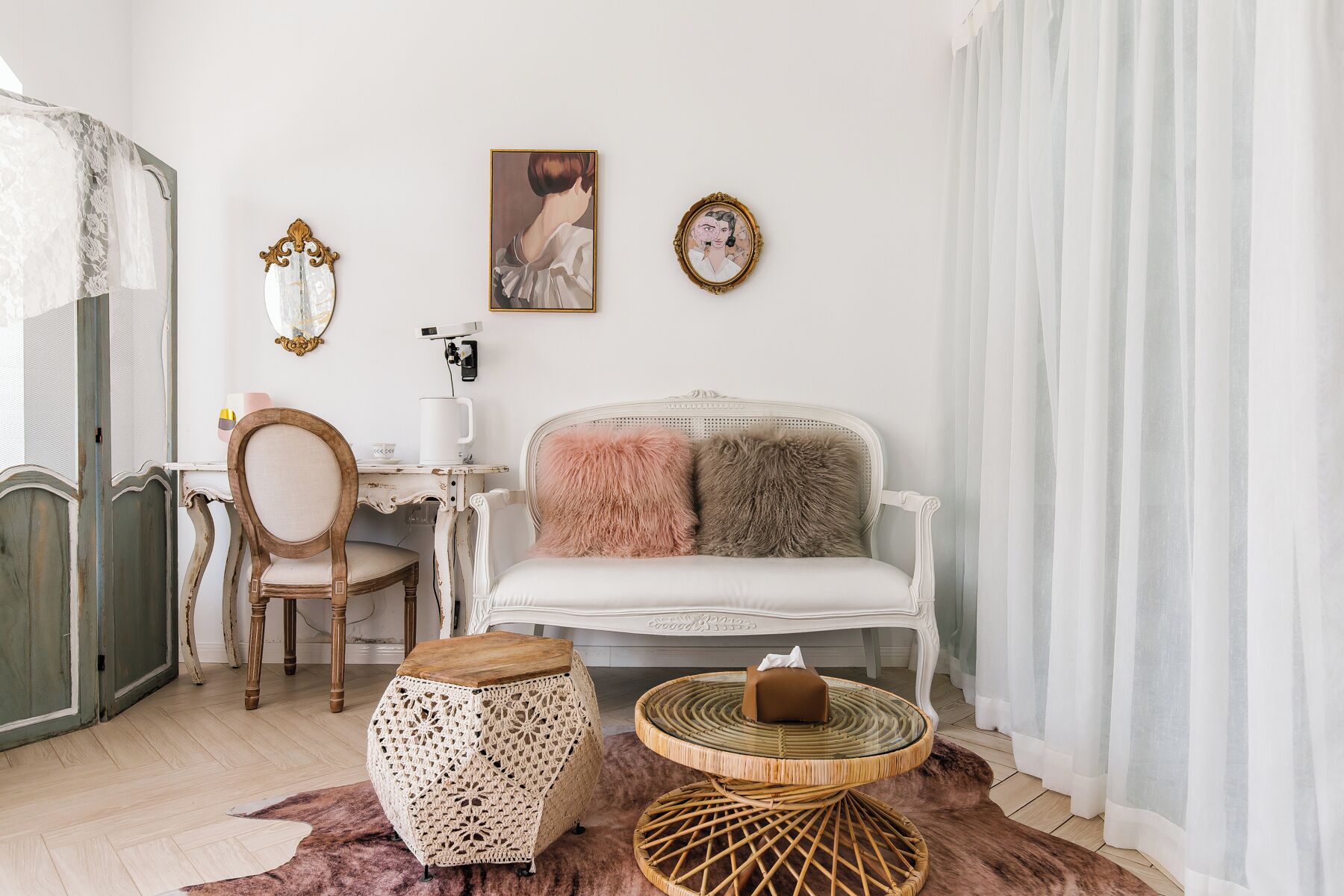 A cozy living room with a white sofa, a wooden chair, a crochet stool, and a wicker side table.