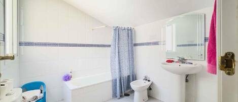 Ein Badezimmer mit Badewanne, Bidet, Waschbecken, Spiegel und Toilette.