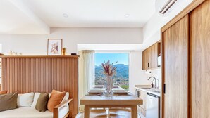 Eine moderne Küche mit Holzausstattung, einem Esstisch für vier Personen und Blick auf eine Berglandschaft durch das Fenster.