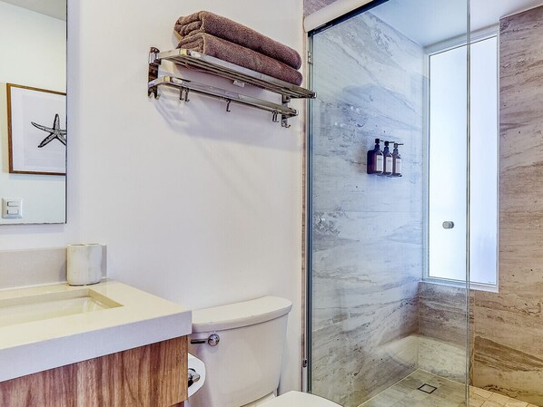 A modern bathroom with a toilet, sink, and glass shower enclosure.