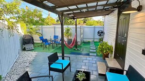 Eine überdachte Terrasse mit Gartenmöbeln, einer Hängematte und einem kleinen Gartenbereich.