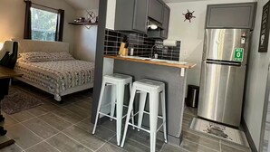 Eine kompakte Küche mit integriertem Kühlschrank, einer kleinen Bar und einem Deckenventilator.