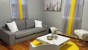 Una sala moderna con un sofá gris, una mesa de centro blanca y detalles en amarillo.