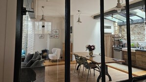 A modern kitchen with a brick wall, wooden cabinets, and a dining area with a table and chairs. - Spacious family house Elegant 6 pers. 3 *|Center and Quiet - Ste Catherine (Honfleur)