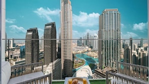 A high-rise hotel room with a city view, a dining table with breakfast, and a balcony with a railing. - Roomszy Forte Residences Downtown Dubai (Dubai)