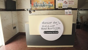 A hotel reception desk with a sign indicating it is a company-serviced hotel. - Hotel Rest O ITPL (Bangalore)