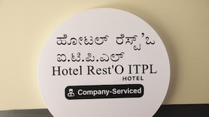 A circular sign with text in multiple languages, including English, stating "Hotel Rest'O ITPL HOTEL" and "Company-Served". - Hotel Rest O ITPL (Bangalore)