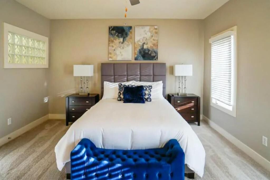 A bedroom with a large bed, two bedside tables, a ceiling fan, and artwork on the wall.