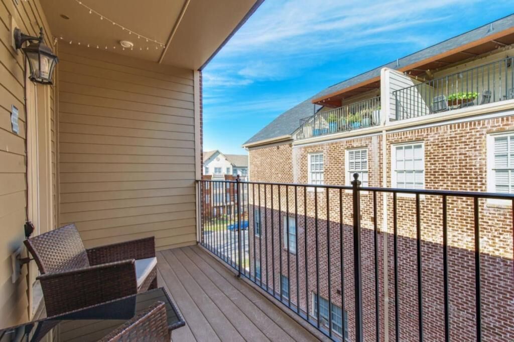 A balcony with wicker chairs, a metal railing, and a view of a brick building with a balcony.