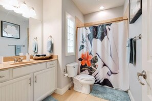 Een badkamer met toilet, wastafel en douchegordijn met bloemendecoratie.