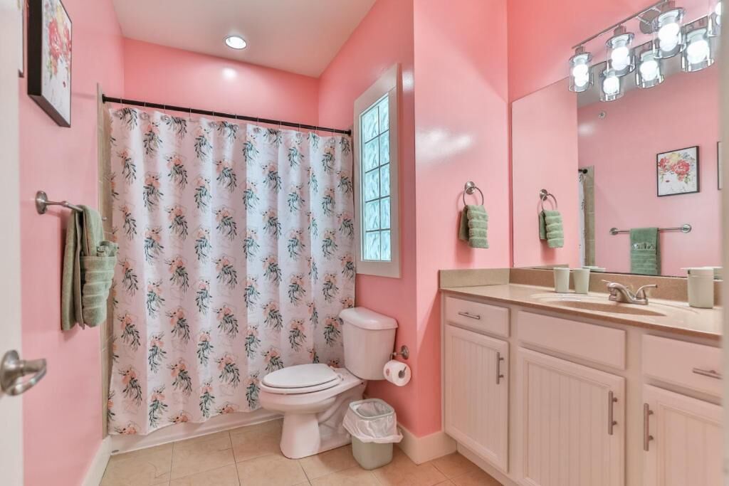 Une salle de bain équipée de toilettes, d’un rideau de douche, d’un lavabo et de meubles de rangement.