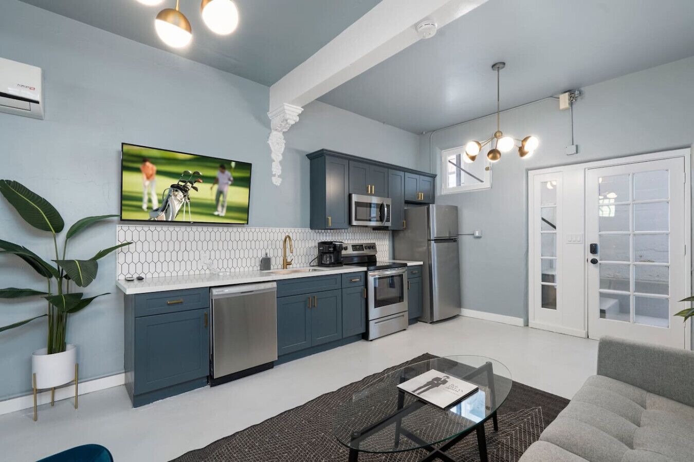 A modern kitchen with dark blue cabinets, stainless steel appliances, and a white countertop.