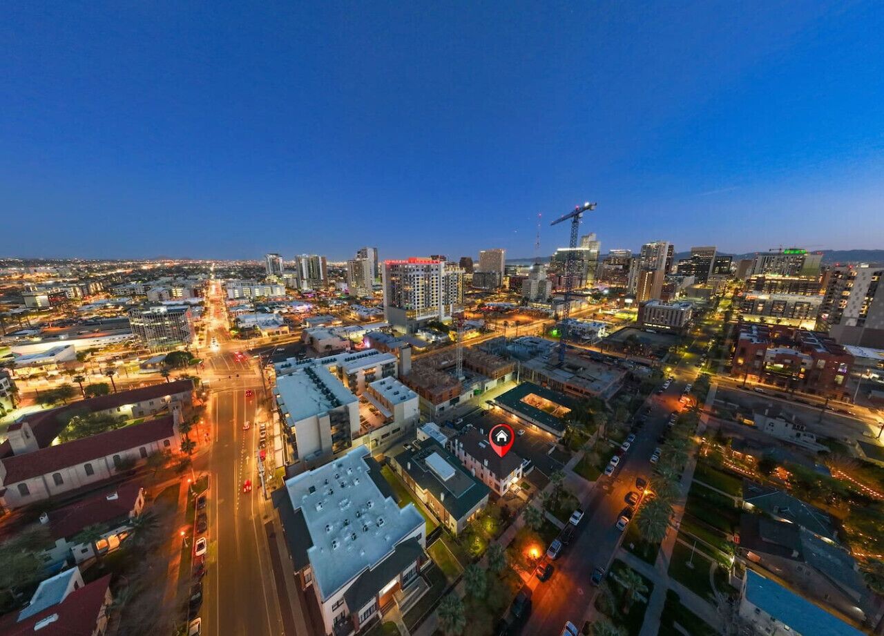 An aerial view of a cityscape at dusk with illuminated buildings and roads.