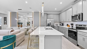 A modern kitchen with white cabinetry, stainless steel appliances, and a central island.